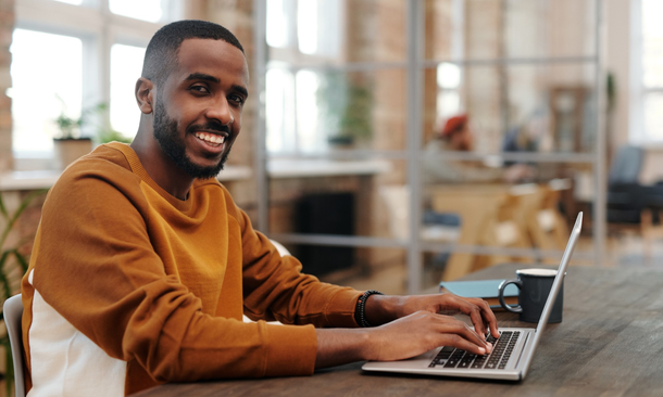 Smiling Man Typing on a Laptop